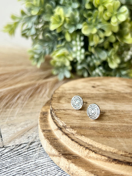 two fine silver stud earrings with a celtic knot design on a wood surface