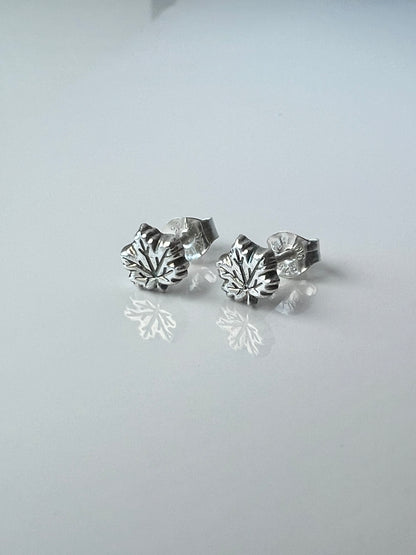 silver maple leaf earrings on a plain white surface