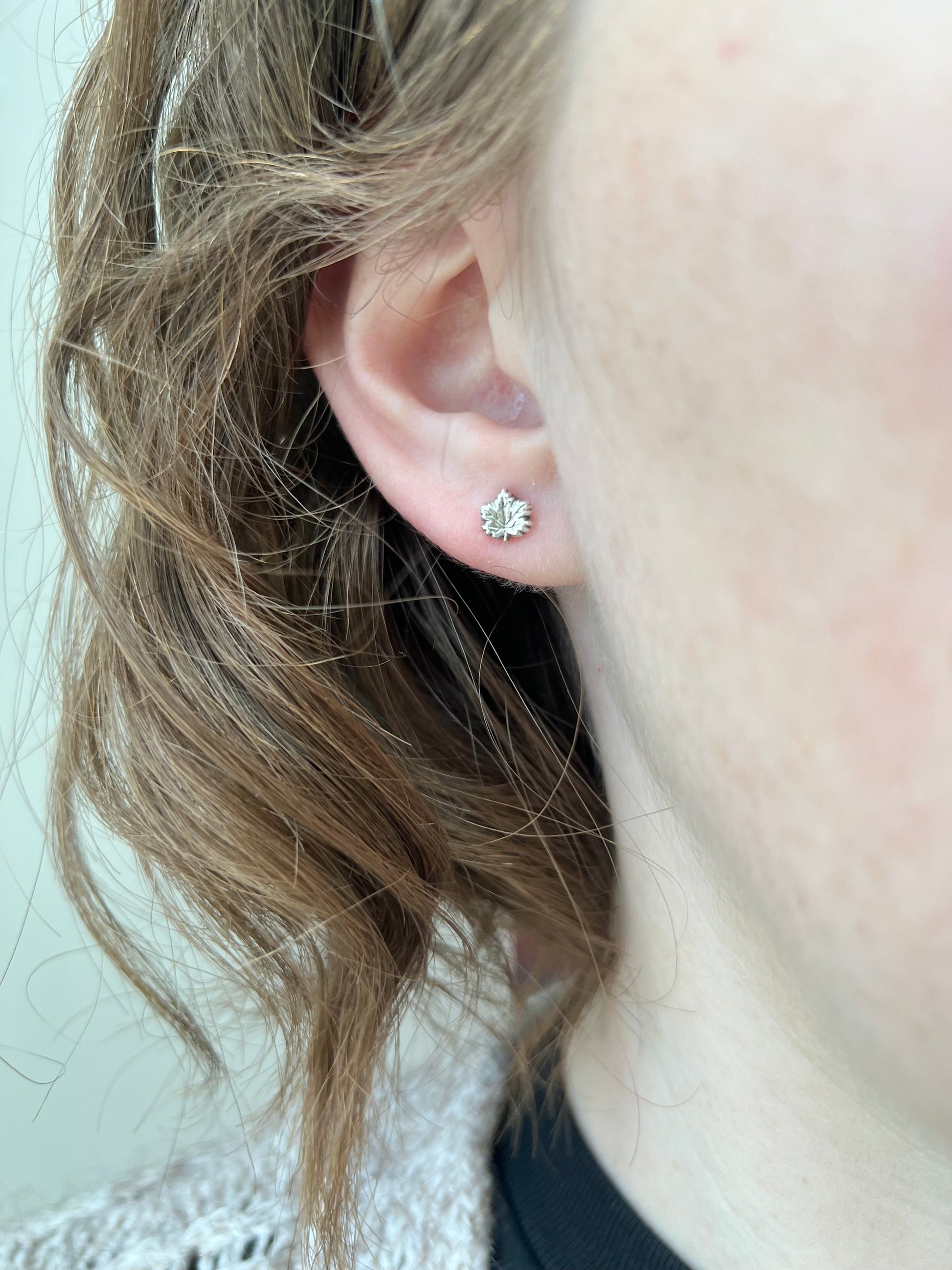 woman wearing a fine silver maple leaf stud earring