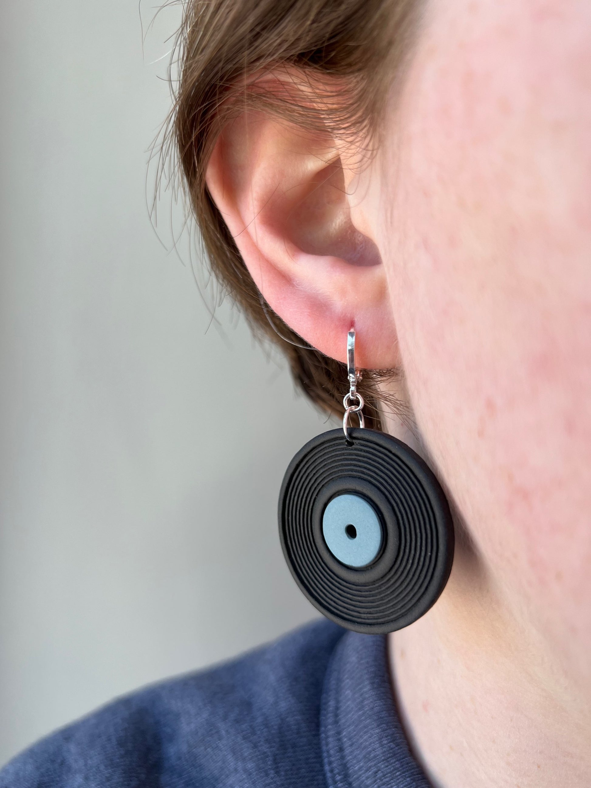 woman wearing a vinyl record earring with a blue label