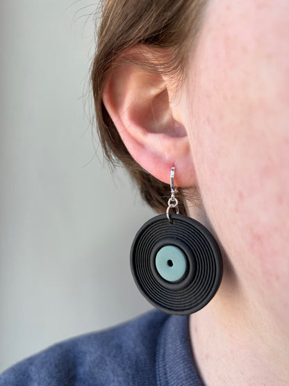 woman wearing a vinyl record earring with a green label