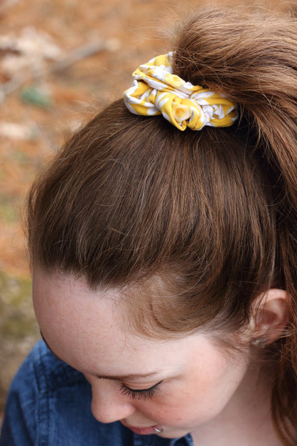 a yellow floral scrunchie holds a woman's ponytail